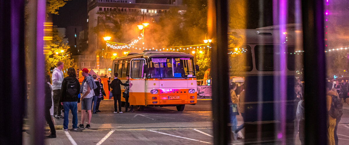 autosan na nocnej wystawie zabytkowych autobusów z klimatycznie oświetloną strefą gastronomiczną w tle