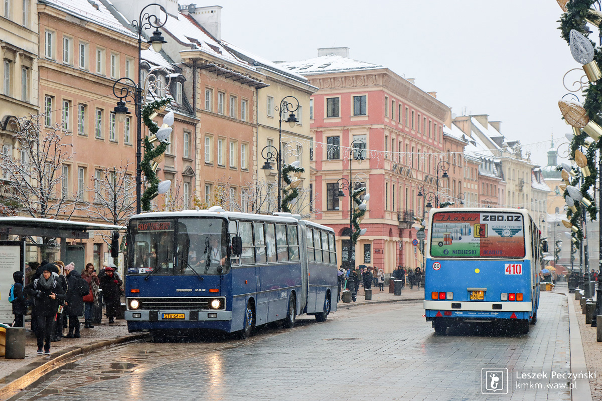 Dwa niebieskie przegubowce mijają się na Krakowskim Przedmieściu